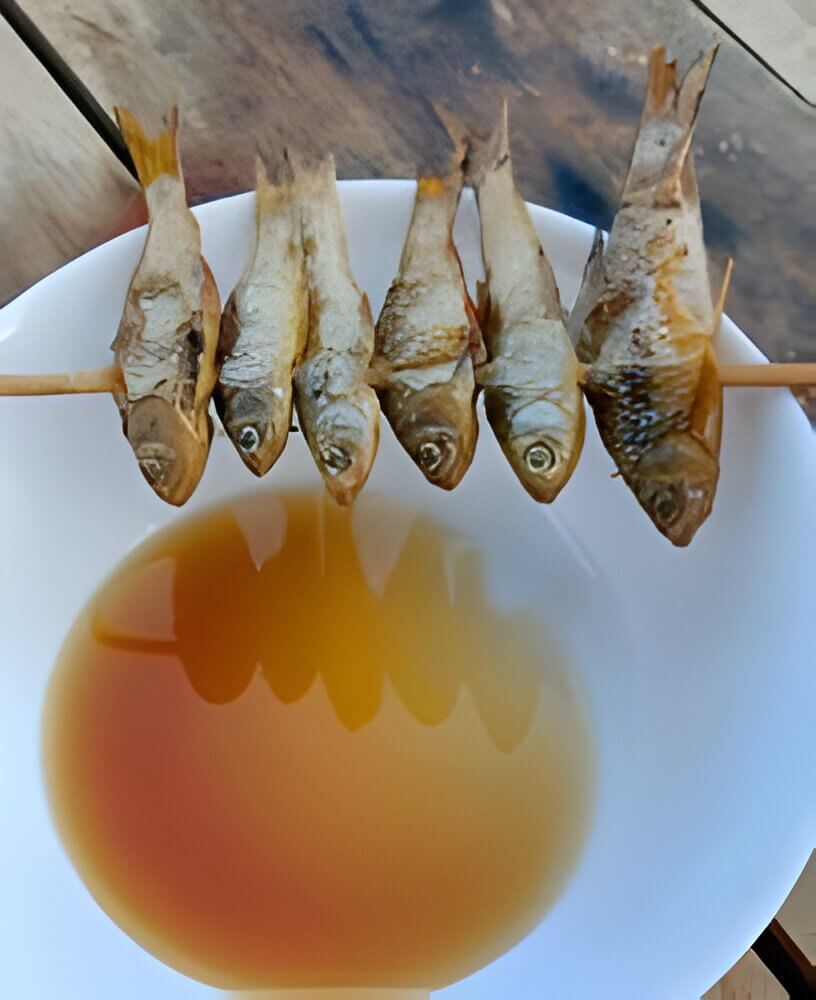 Asian-style fish snack on a stick dipped in a savory sauce.